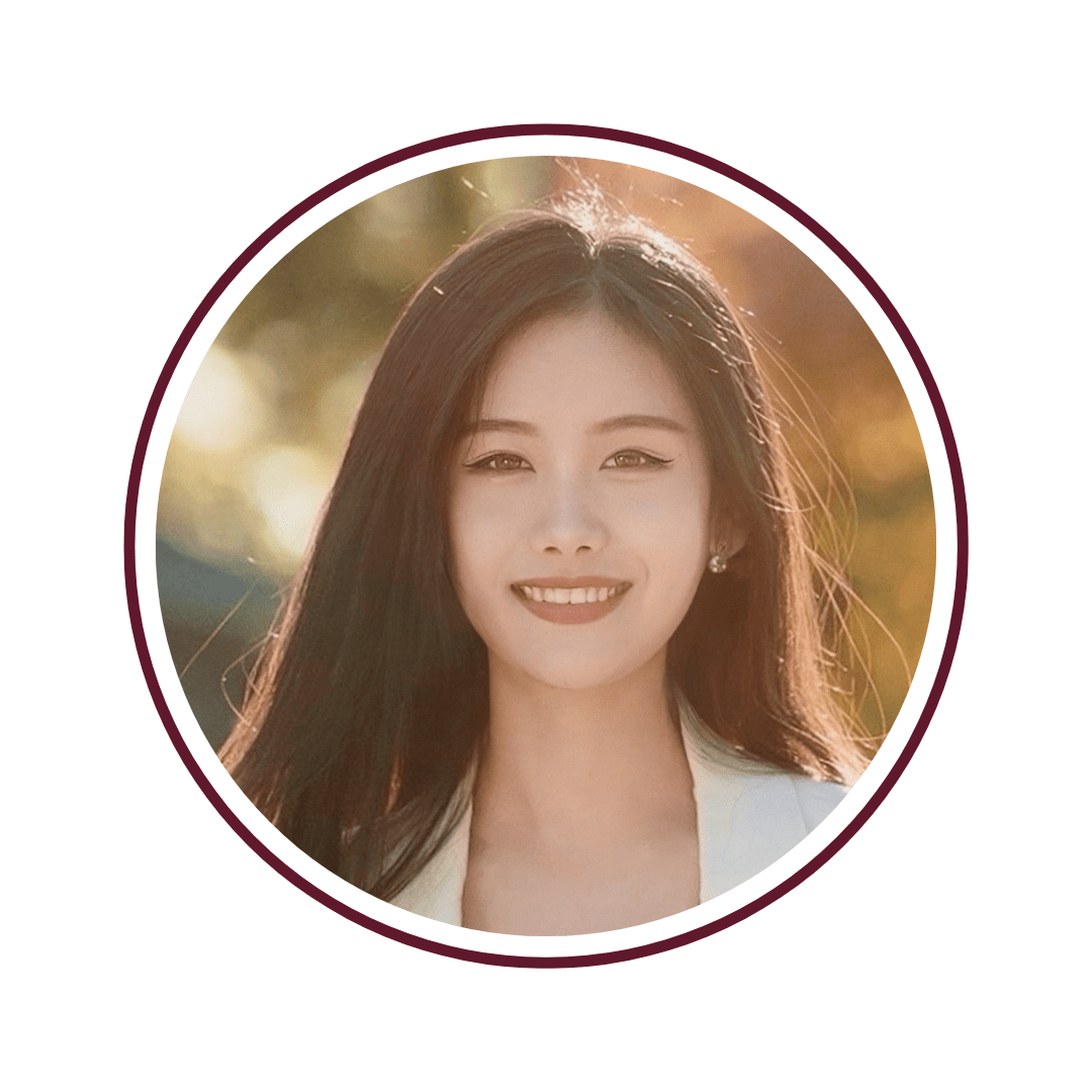 Picture of dark-haired smiling woman in cream blazer in front of blurred light background. The picture is bordered by a maroon circle. 