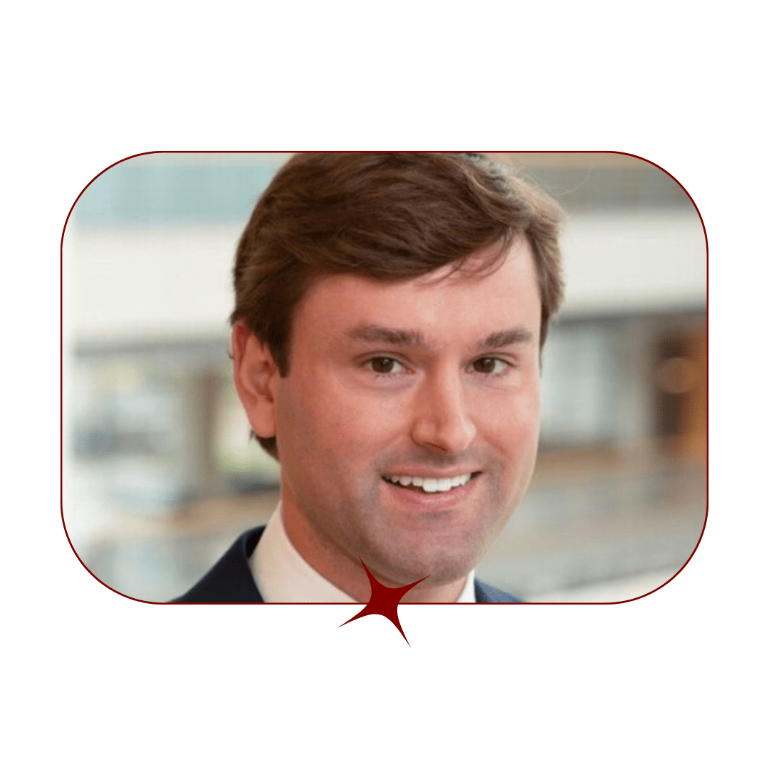 Picture of a young, smiling, brown-haired man wearing a suit and tie in front of a blurred, wooden background. The picture is bordered by a thin, red-lined frame with a red star in the center. 