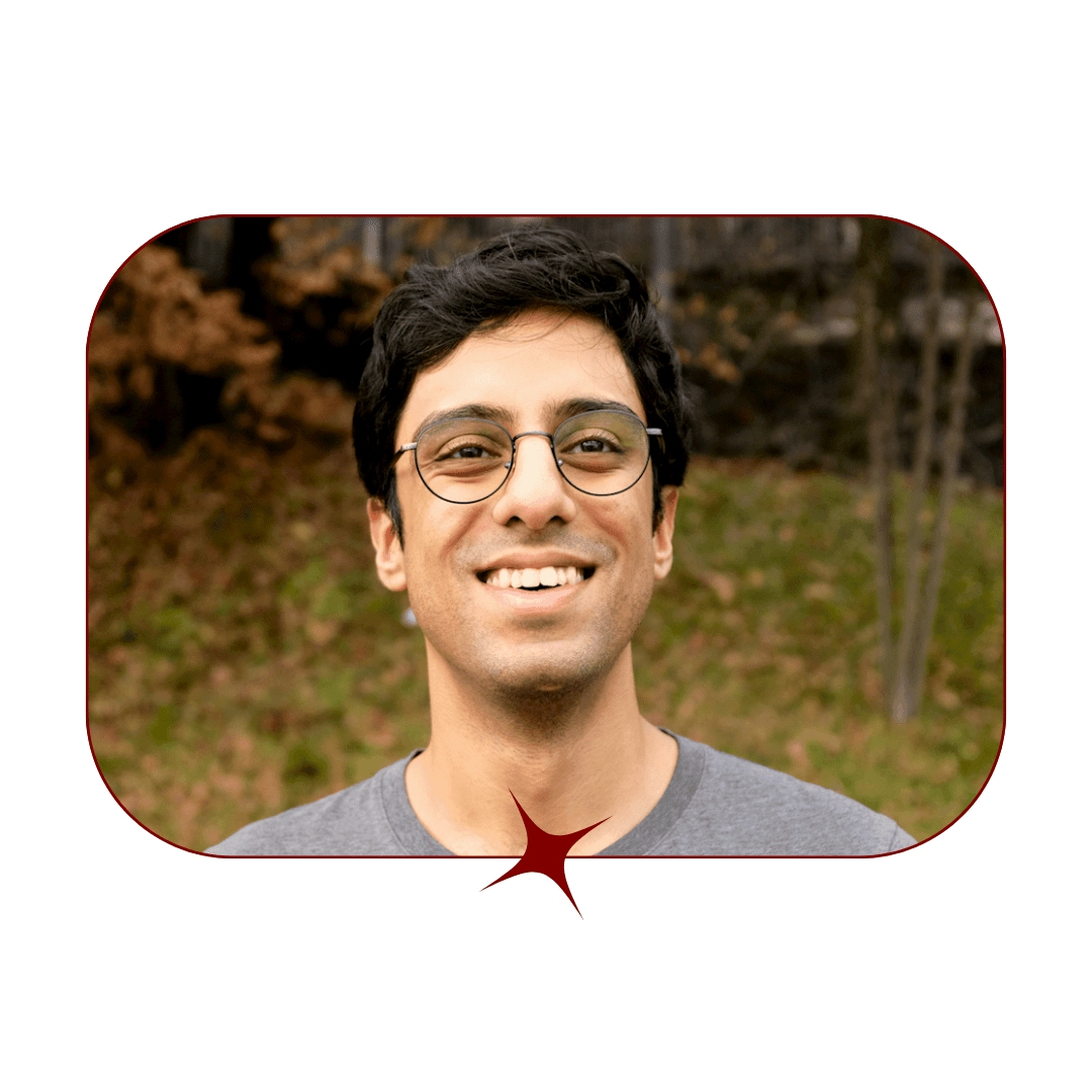 Picture of a young, smiling, dark-haired man wearing glasses and a grey shirt in front of a blurred fall-leafed background. The picture is bordered by a thin, red-lined frame with a red star in the center. 