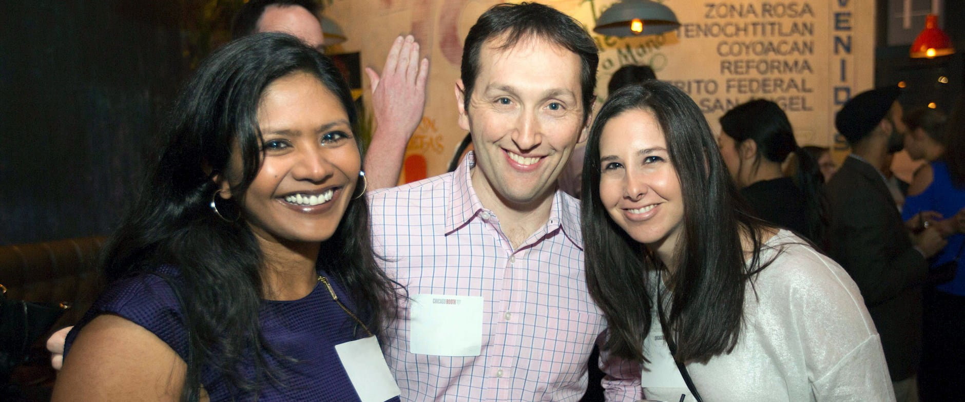 Three Booth MBA alum posing at an event