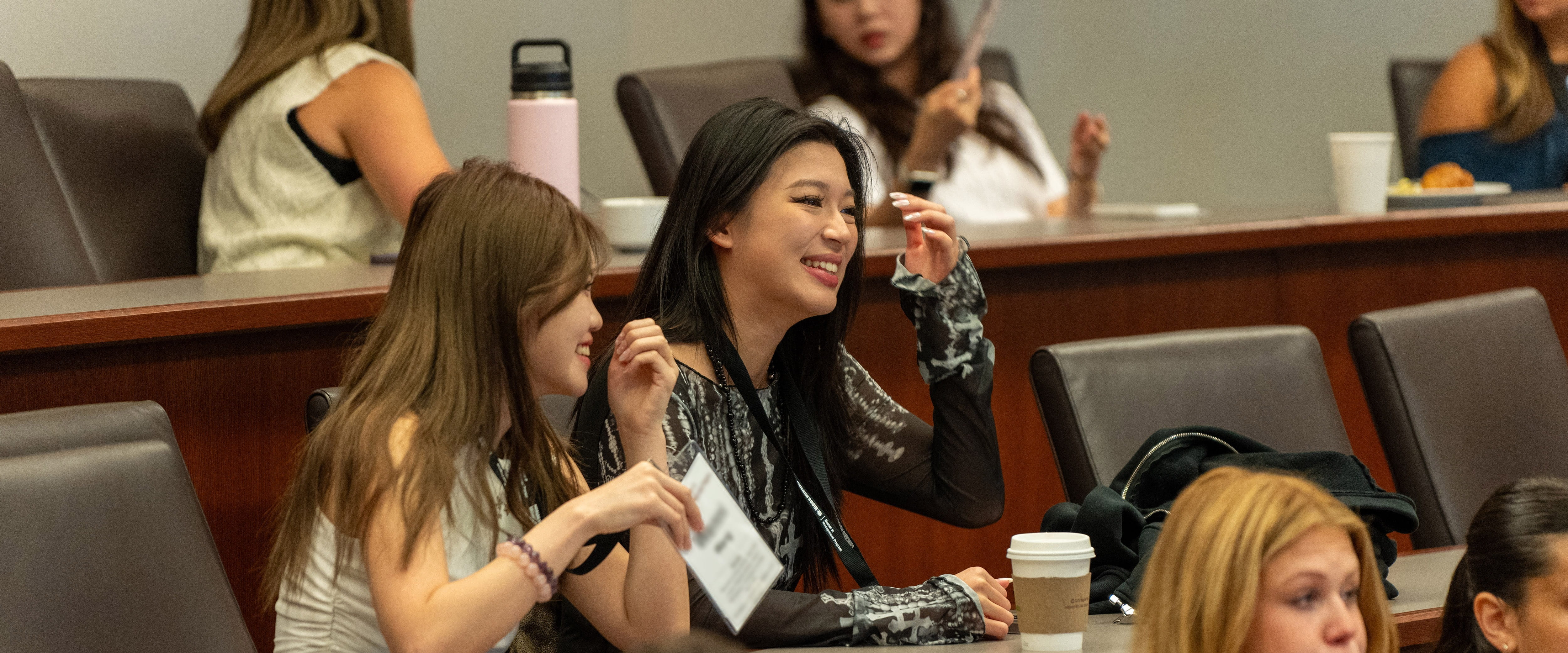 Two students in classroom smiling during lecture.