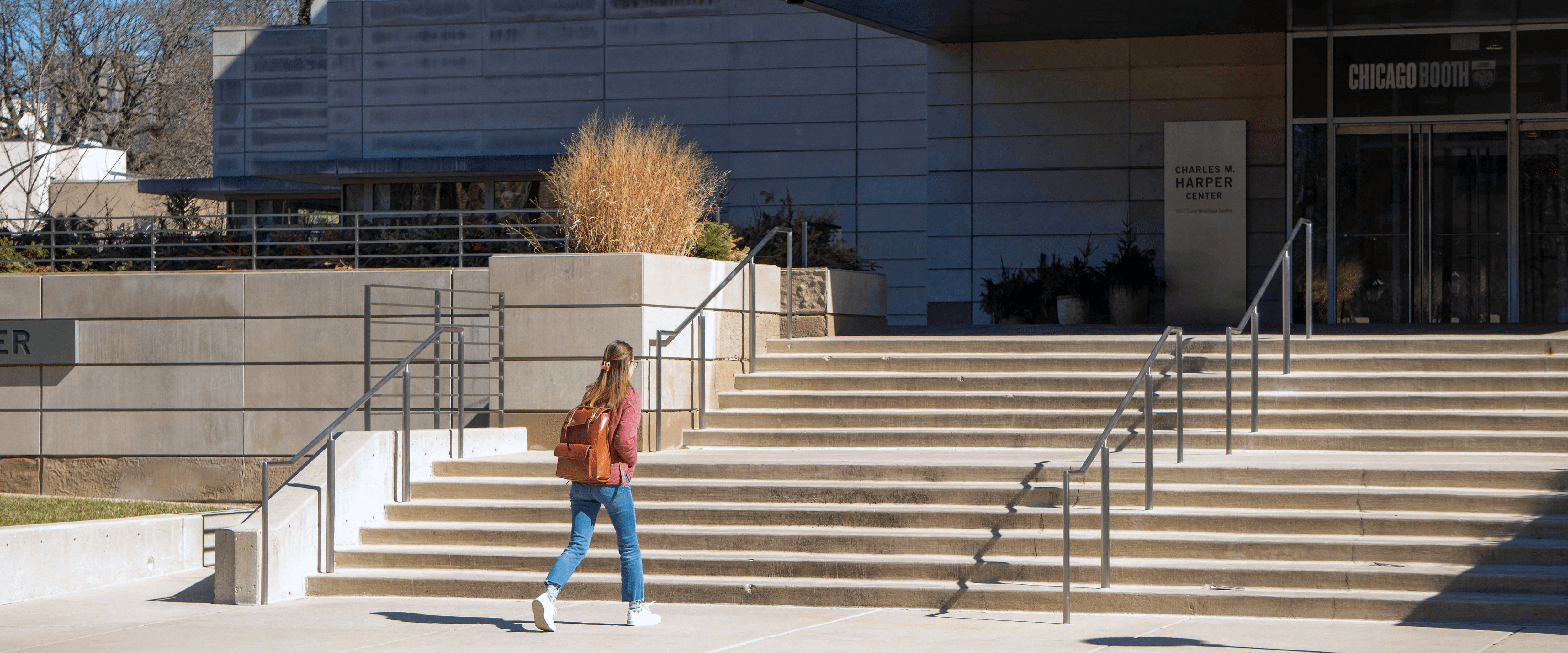 A student walking into the Harper Center on a sunny day. 