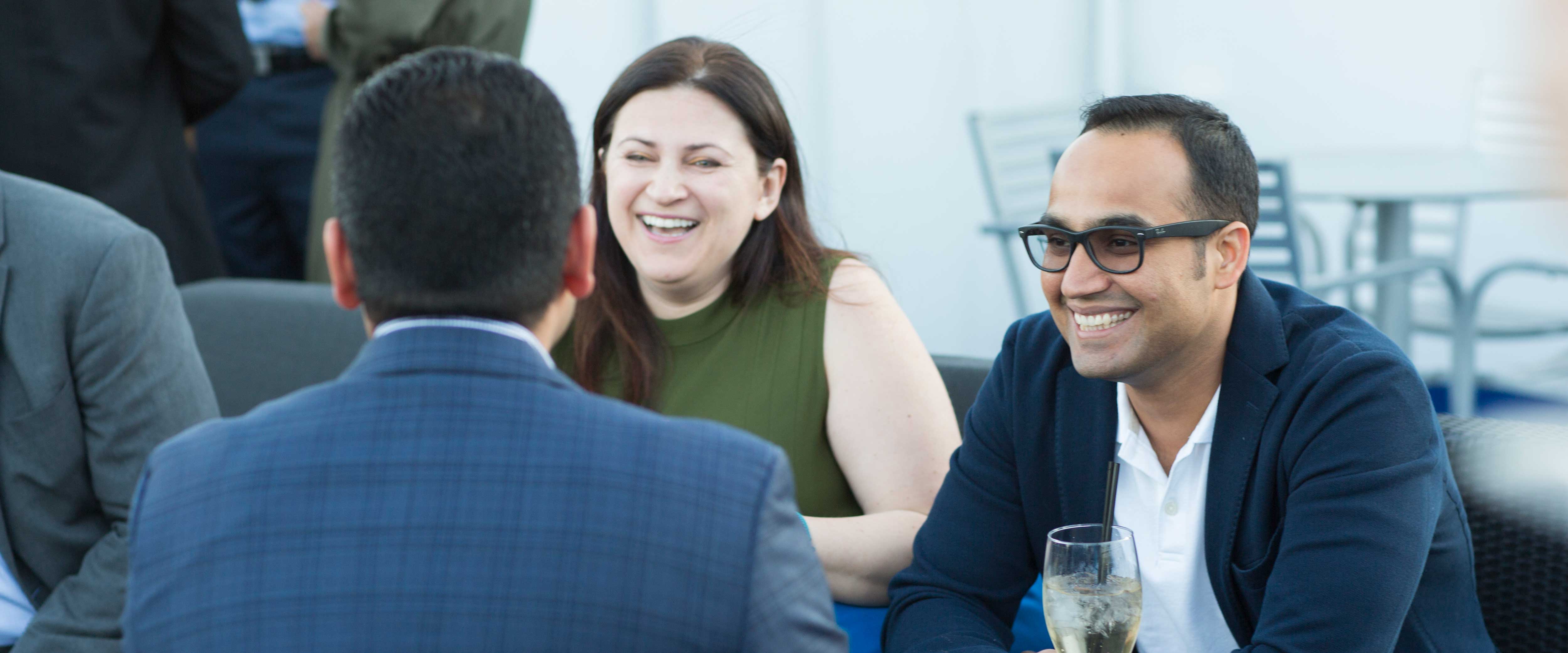 A man and woman speaking with a man with his back to the camera