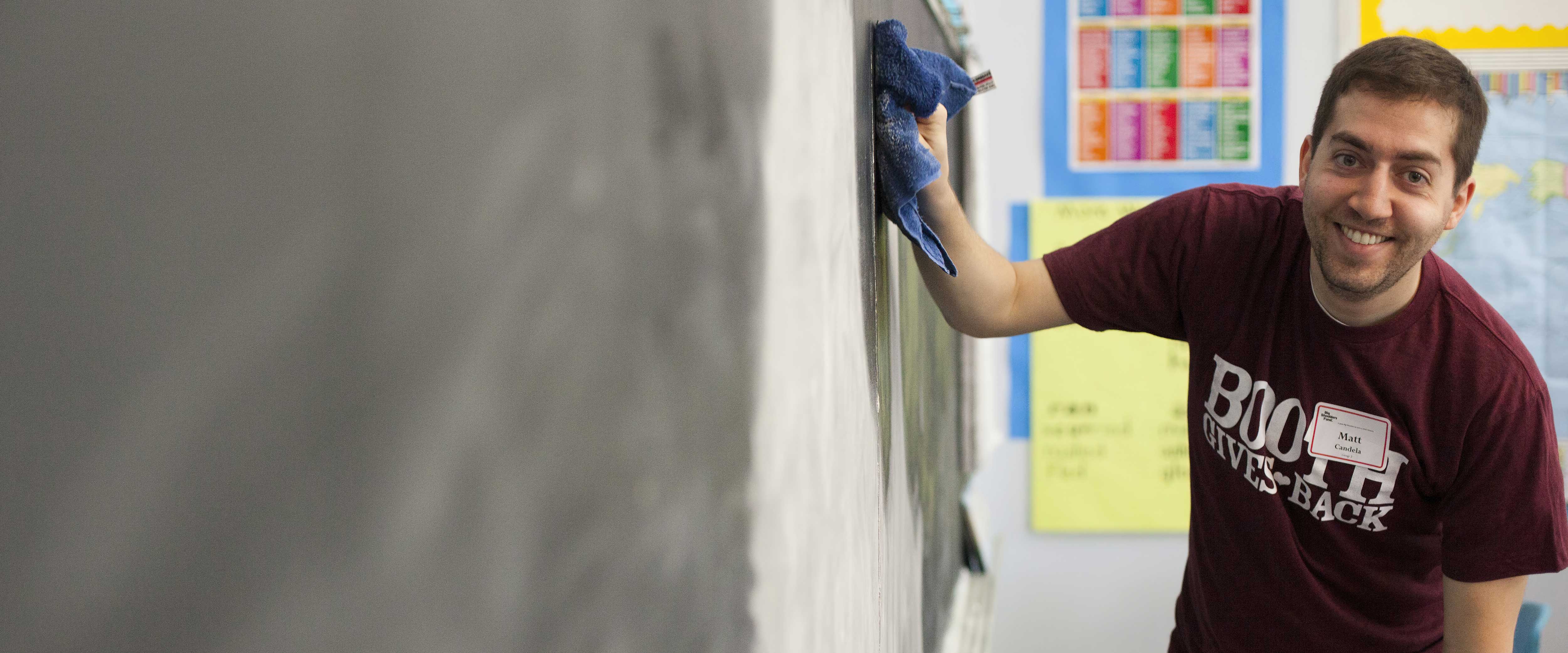 Matt Candela cleaning a blackboard during Booth Gives Back
