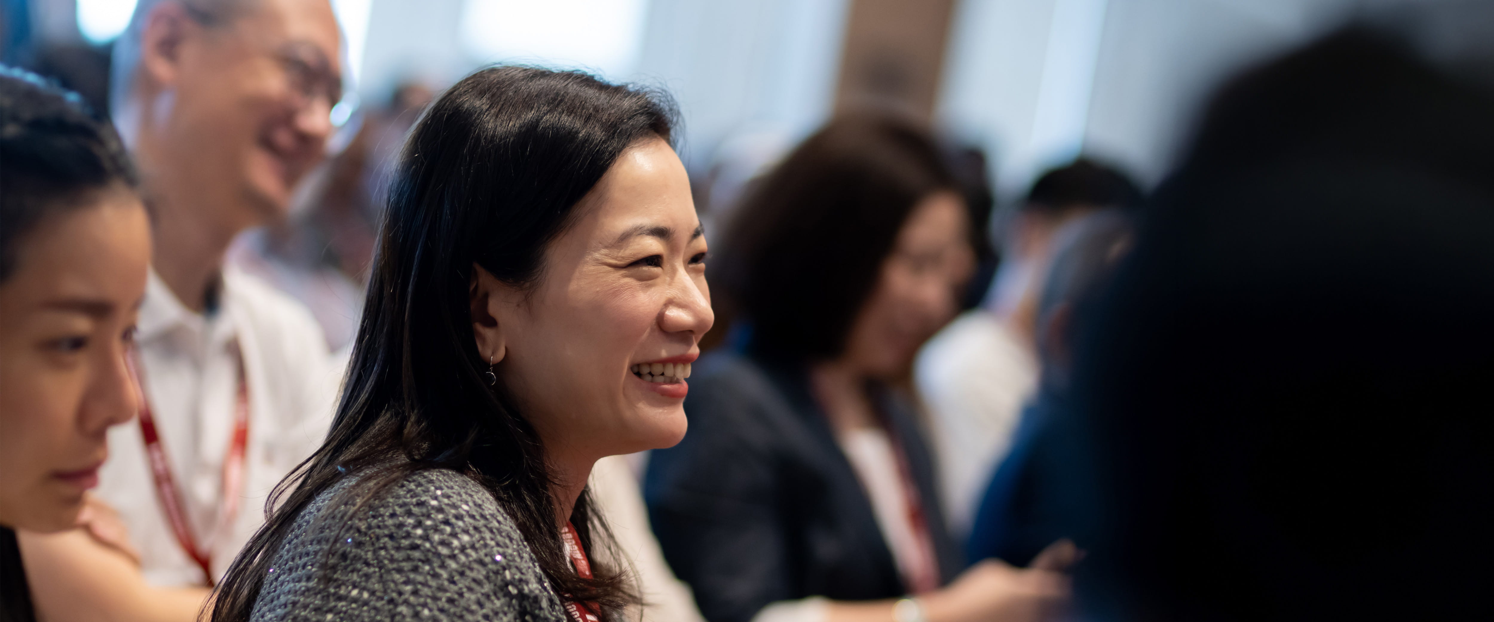 Asian woman in a crowd, smiling during an event