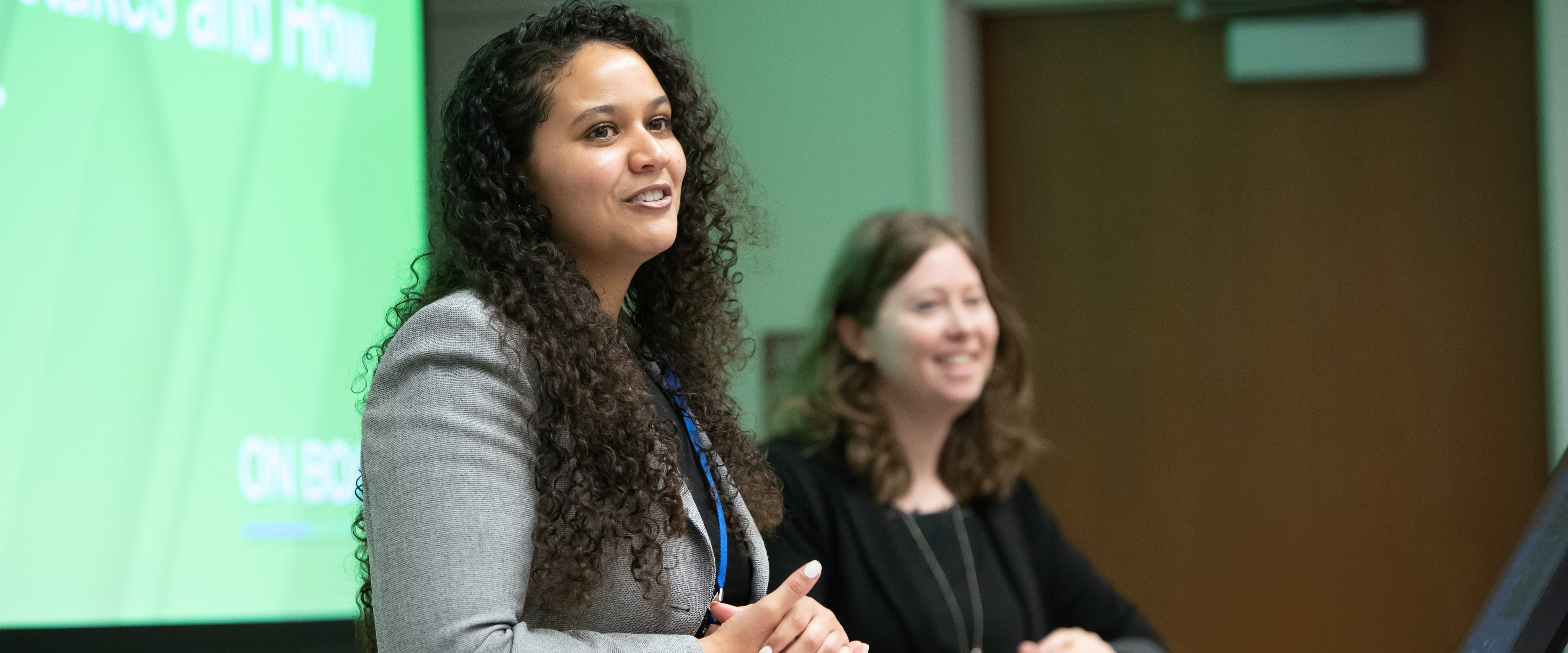 Two students smile as they give a presentation in front of a class.