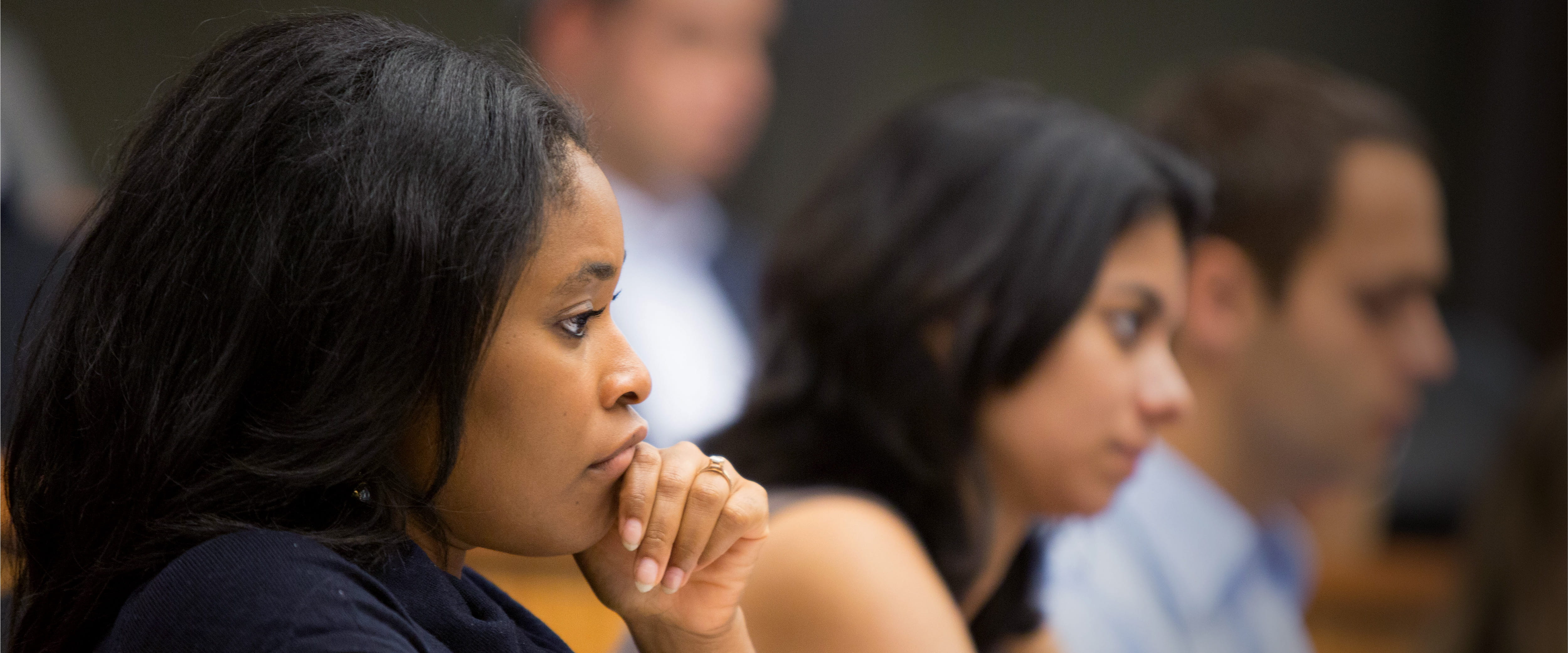 A student rests her hand on her chin in a classroom full of students. 