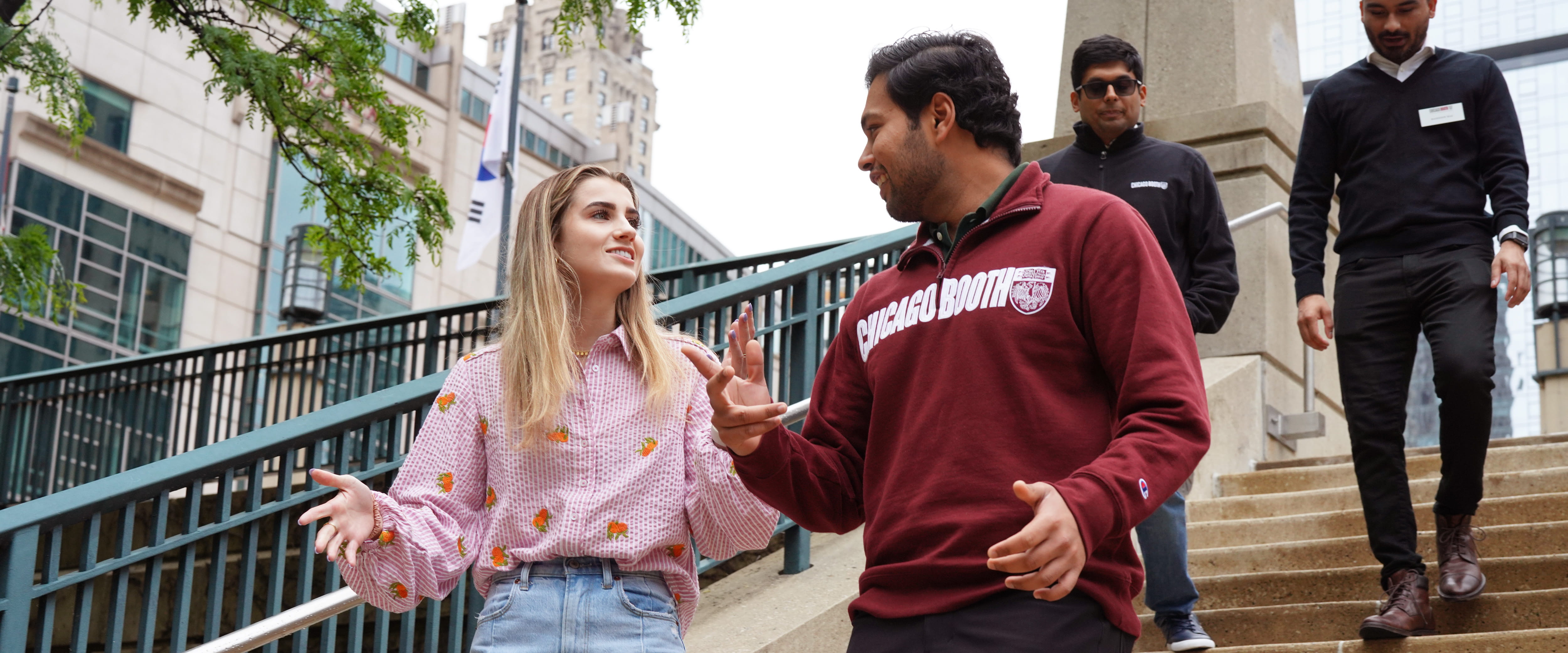 Two students chatting while walking down the steps near the Gleacher Center