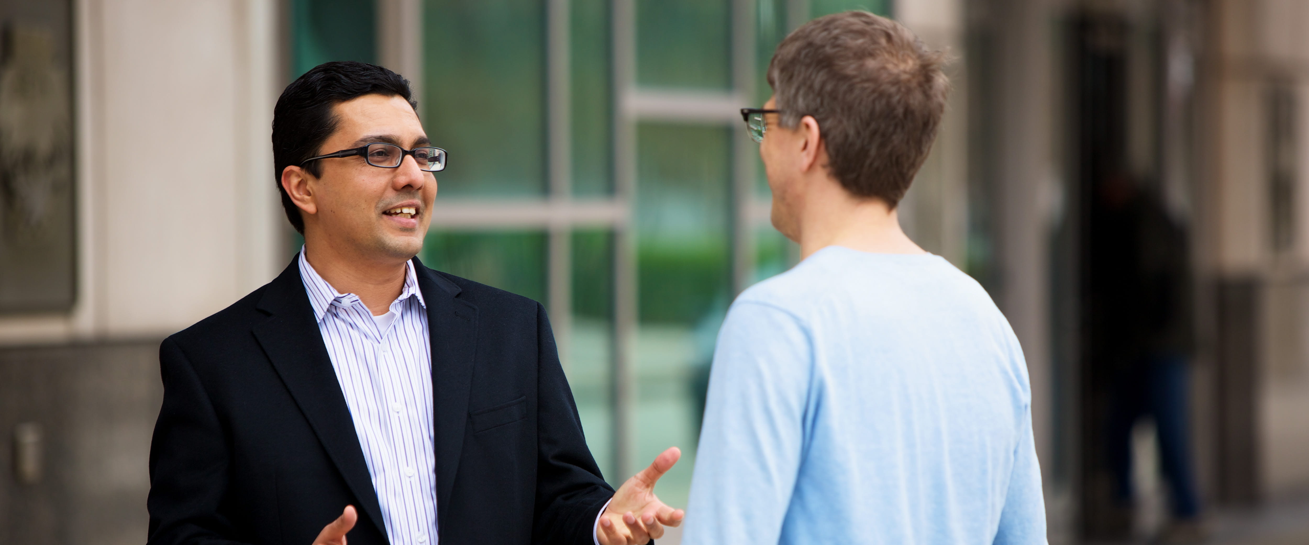 Two students converse while standing outside of Gleacher Center. 