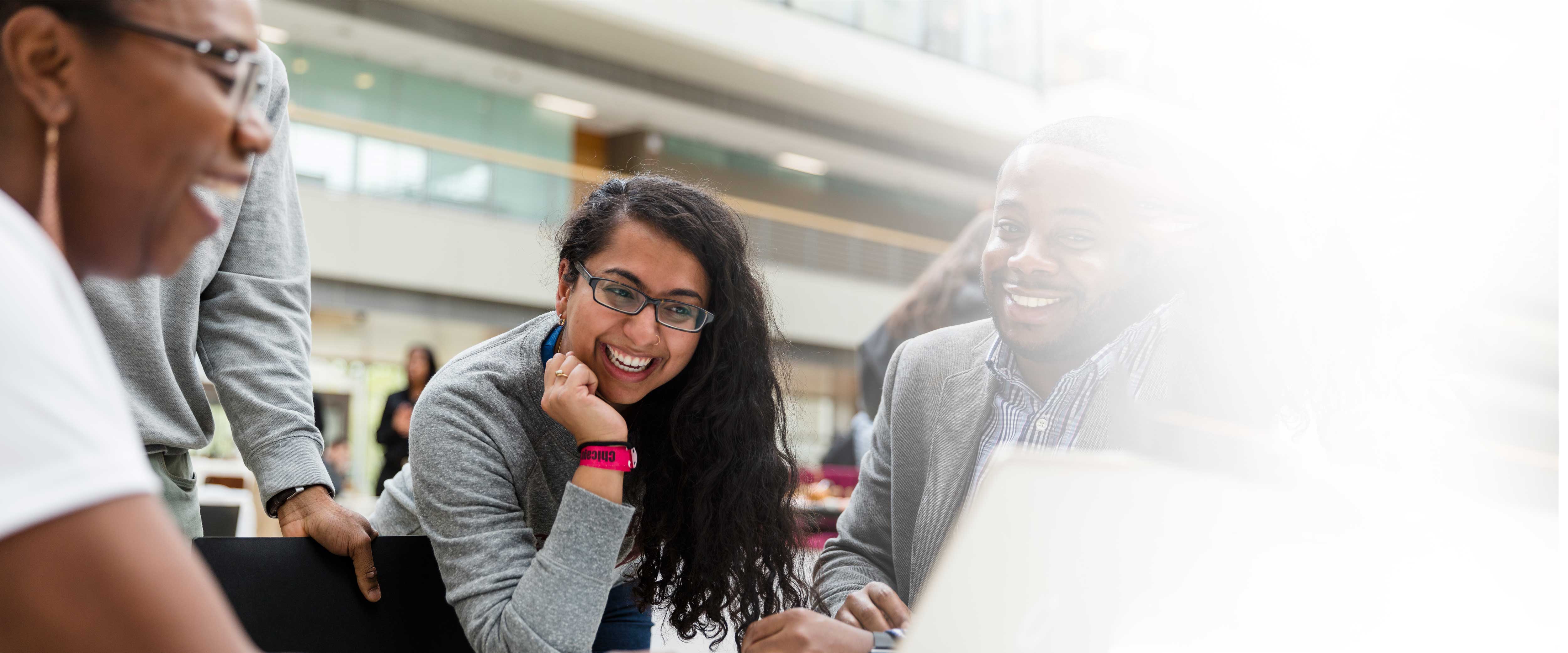 Two women and man in the winter garden looking at a laptop laughing