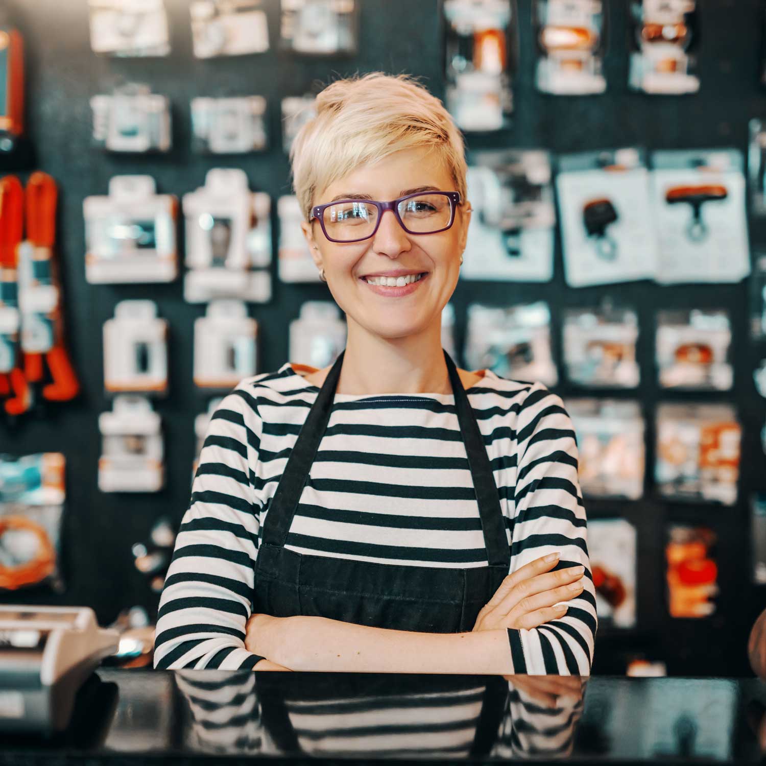 Woman with apron smiling behind a business countertop