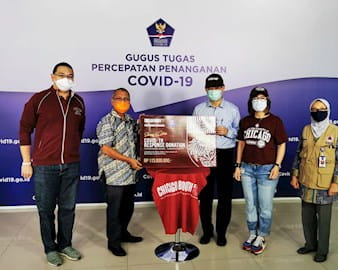 Members of the alumni club of Indonesia pose with a donation for COVID relief efforts