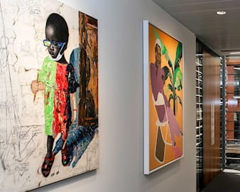 Two pieces of art hanging in a sunny hallway at the London Conference Centre; one depicts a small child with a mask around their chin and the other a woman sitting on a folding chair