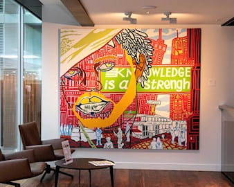 A large, colorful canvas depicting a face & cityscape with the words "Knowledge is a Strength" across the work. It's situated by a window at the London Conference Centre.