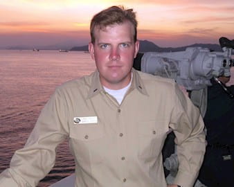 John Taplett posing in uniform in front of a sunset 
