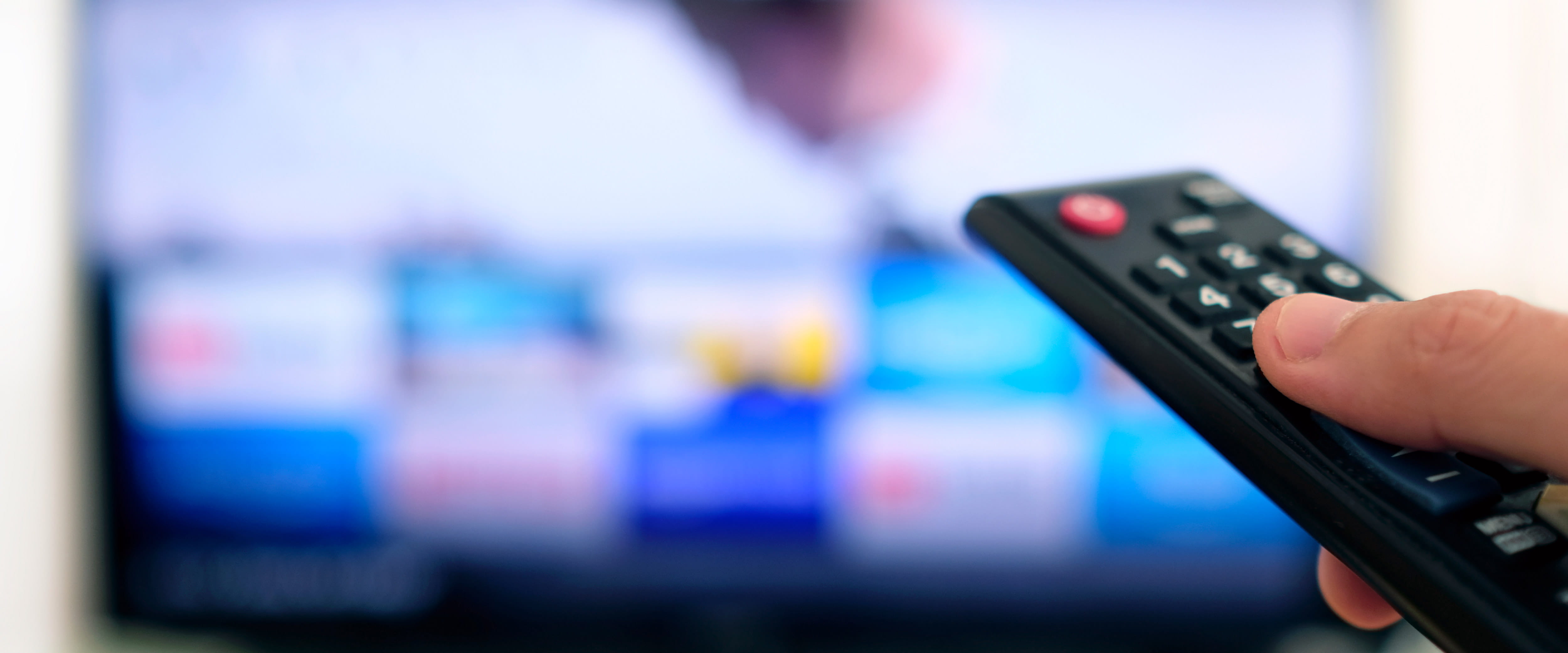 Hand holding remote pointed at TV