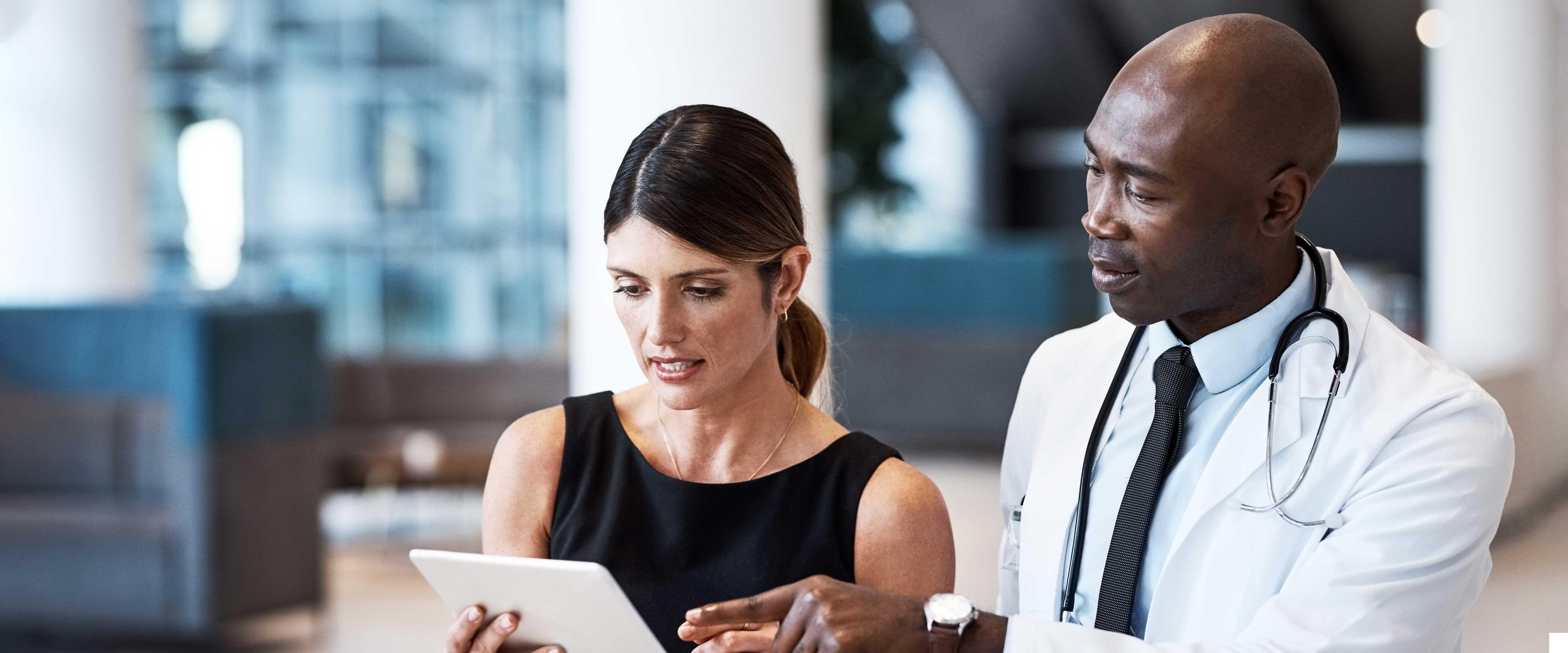 Female hospital worker with a doctor reviewing an iPad screen
