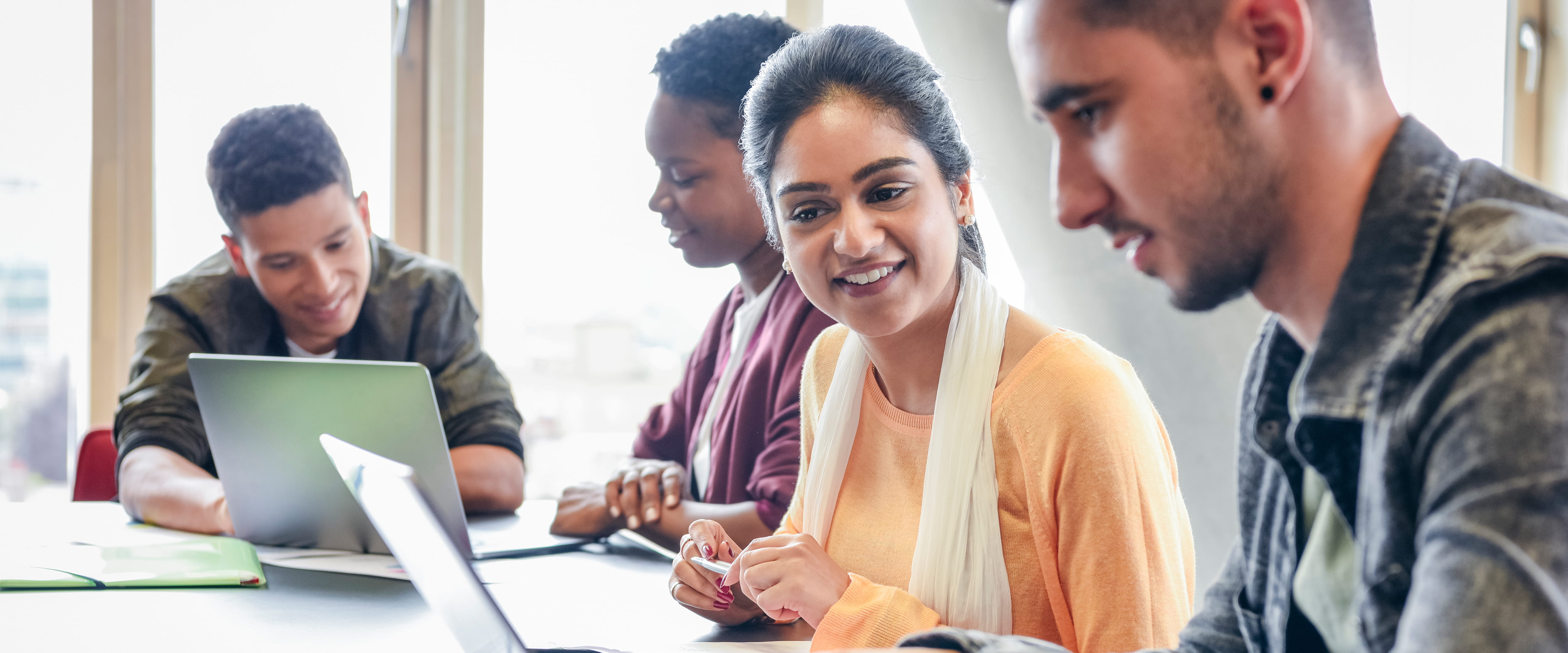 Undergraduate students collaborating with eachother on their laptops