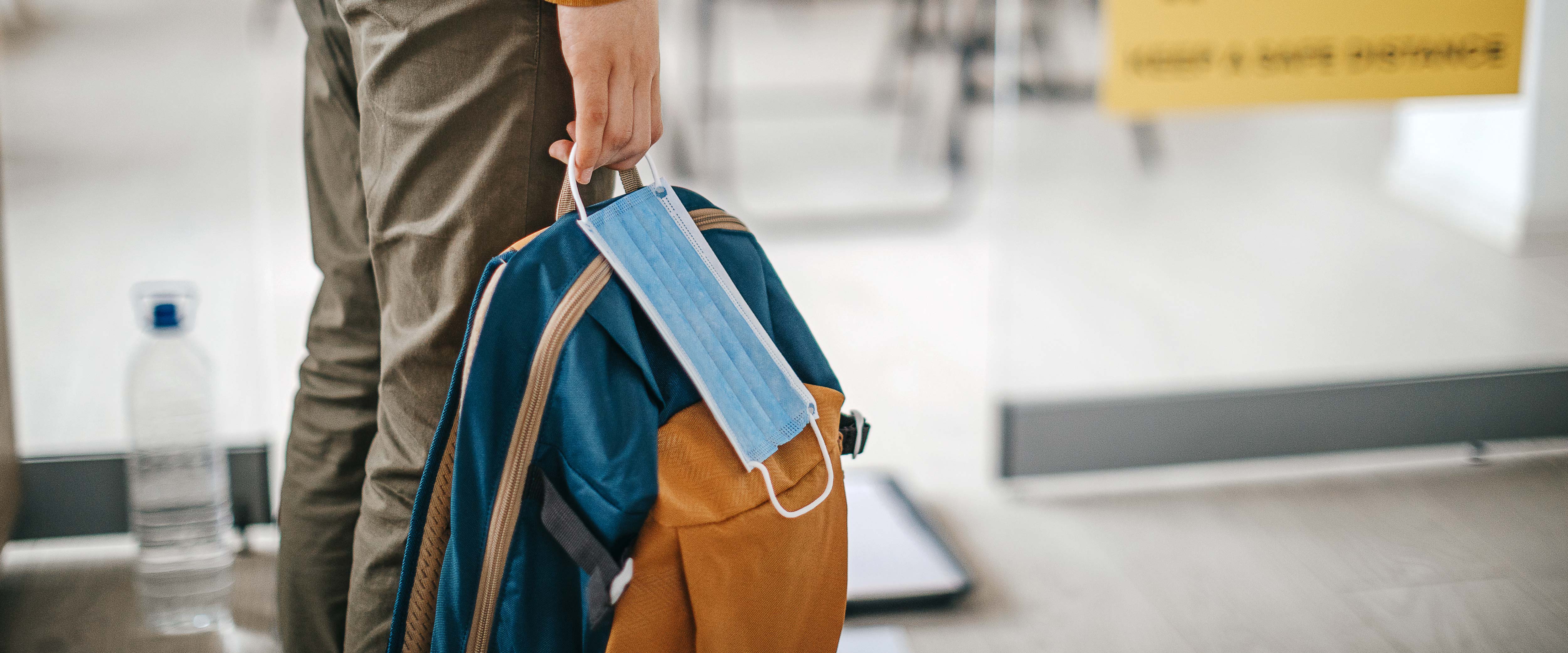 Man walking with a bag and a mask at the ready