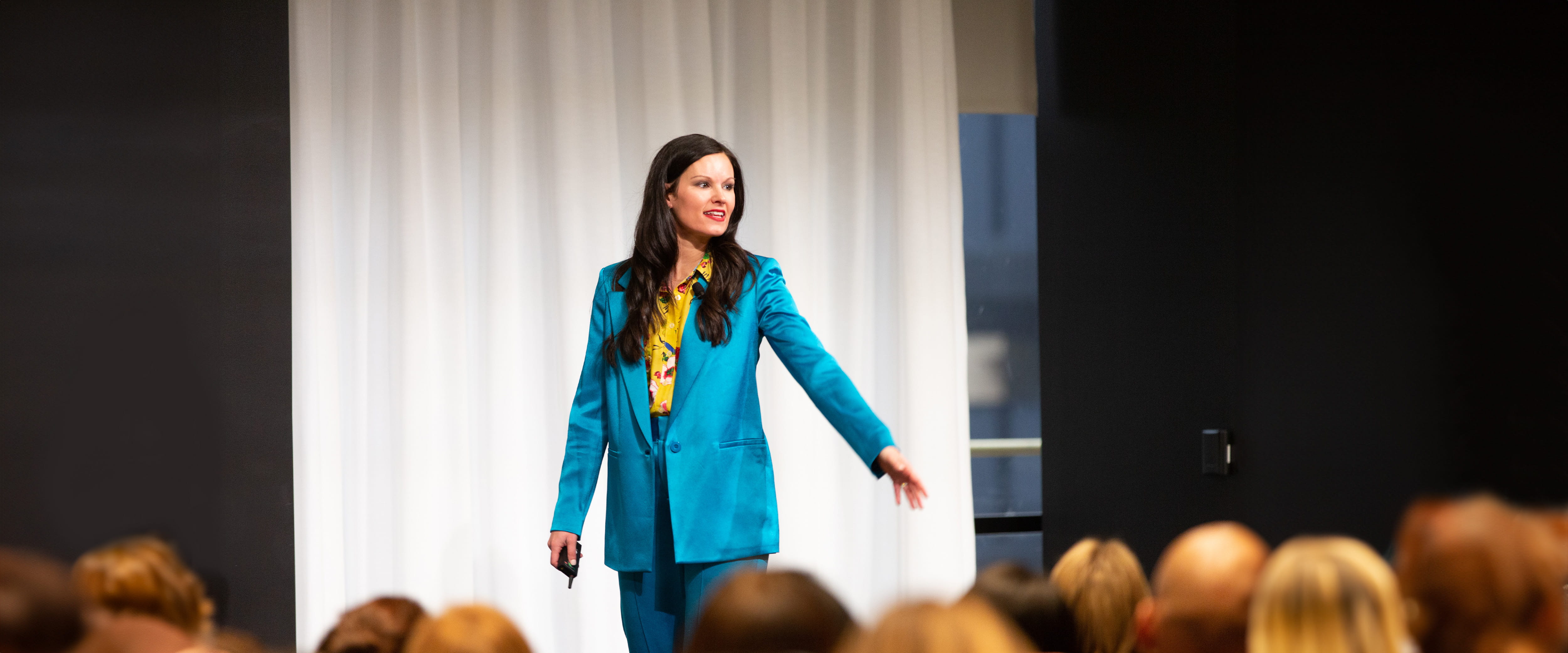 Erin Diehl speaking on stage in a blue suit
