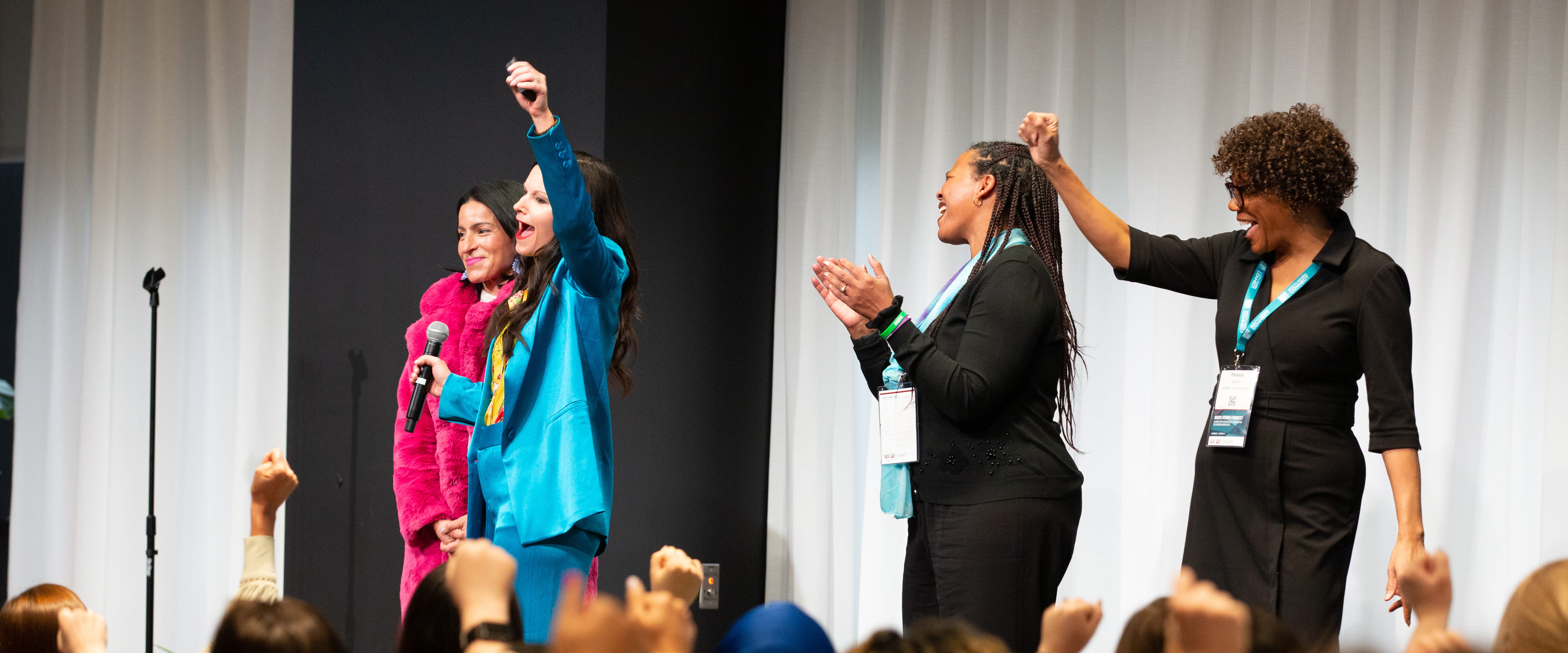 Erin Diehl cheering on stage with three female volunteers