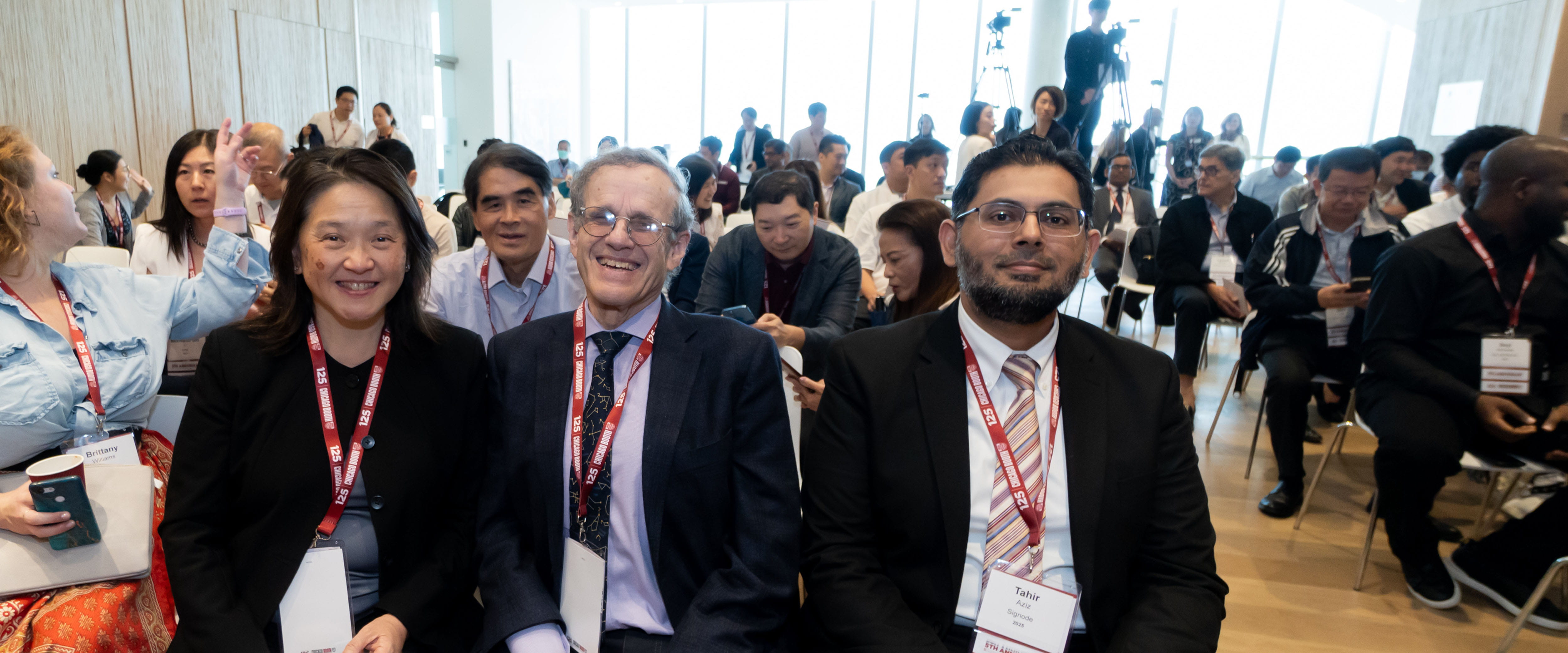 Three Chicago Booth Hong Kong faculty members smiling for the camera at an event