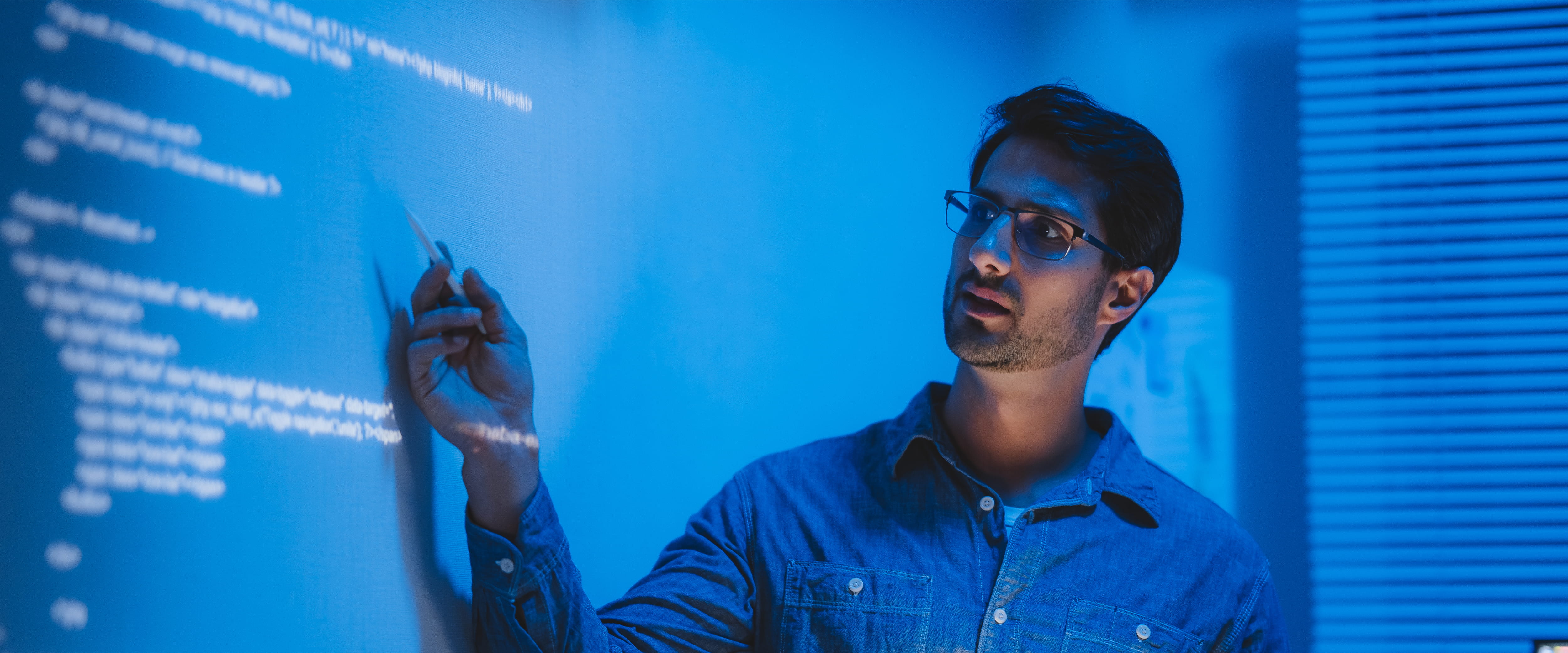person presenting in dark room with projector screen