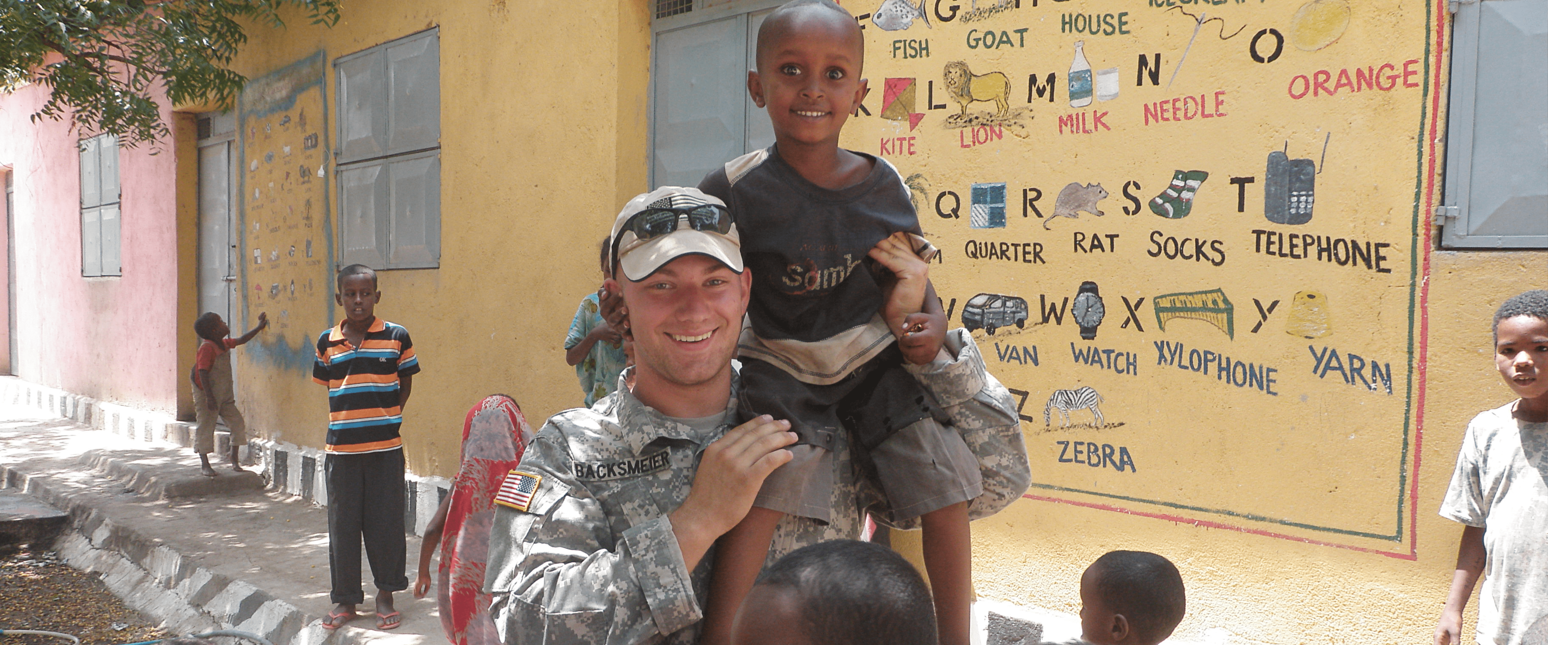 Ben Backsmeier at a school with a child on his shoulder.
