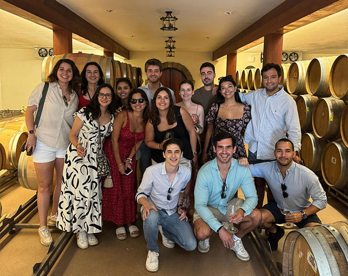 group of Boothies, including Nehir Mentes, in wine cellar smiling in group