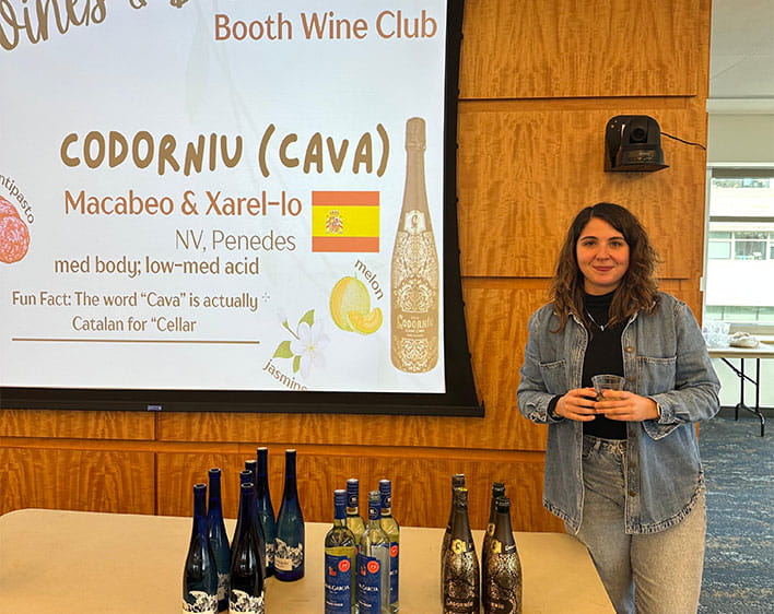 Nehir tabling at wine event with wine on table and signage behind her