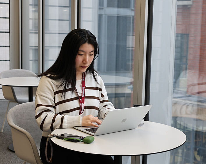 Weirong Deng sitting down at table on laptop