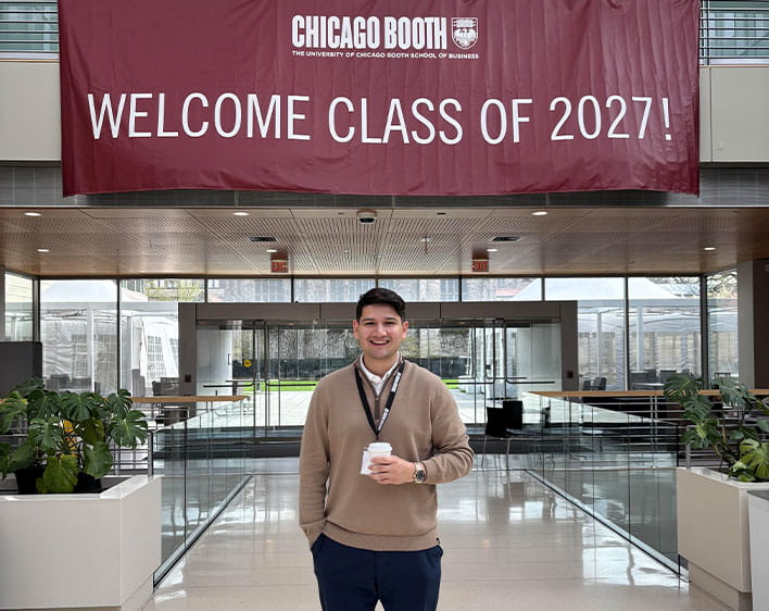 Tyler Stewart in front of welcome class of 2027 sign on his first day at Booth
