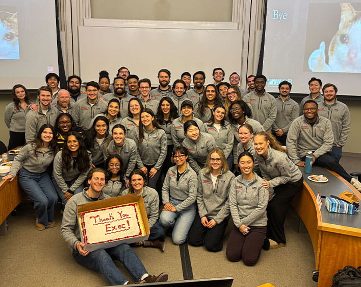 GBC sendoff event with group of Boothies in classroom wearing matching grey Booth branded jackets