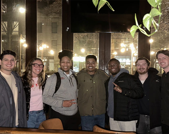 Tyler Stewart and members of the Graduate Business Council smiling togther at event