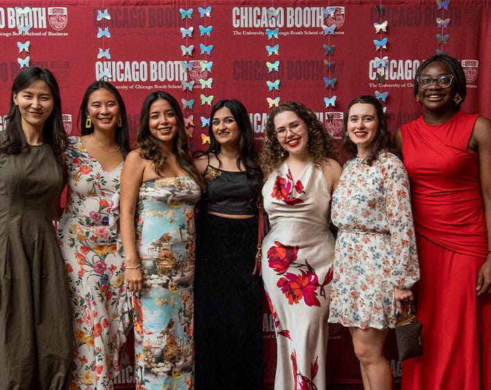Selena and other CWIB members smiling in front of Chicago Booth banner in formal wear
