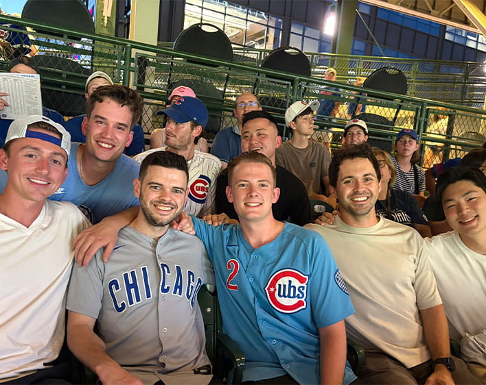 Mayes Lane at Cubs baseball game with friends sitting down while smiling