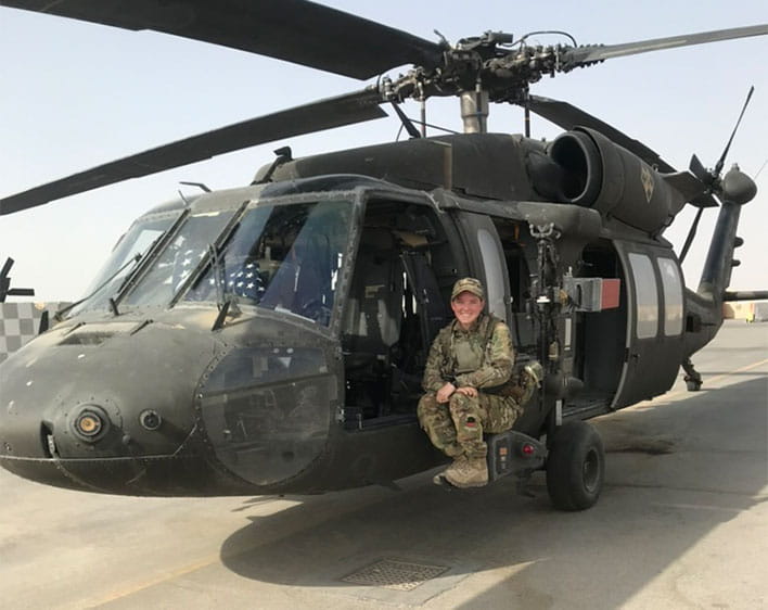 Madison Davis with military uniform on next to helicopter
