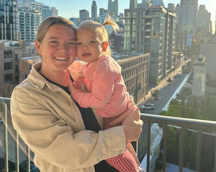 Madison Davis smiling with her daughter outside with glimpse of Chicago skyline in background