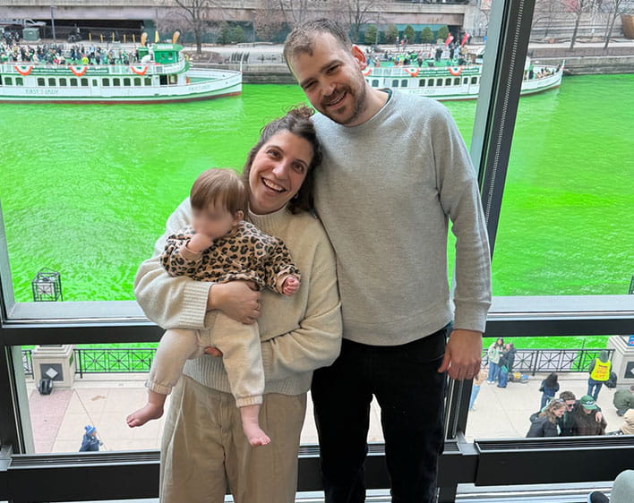 Naama Elazar with her husband and daughter with the green Chicago river in background