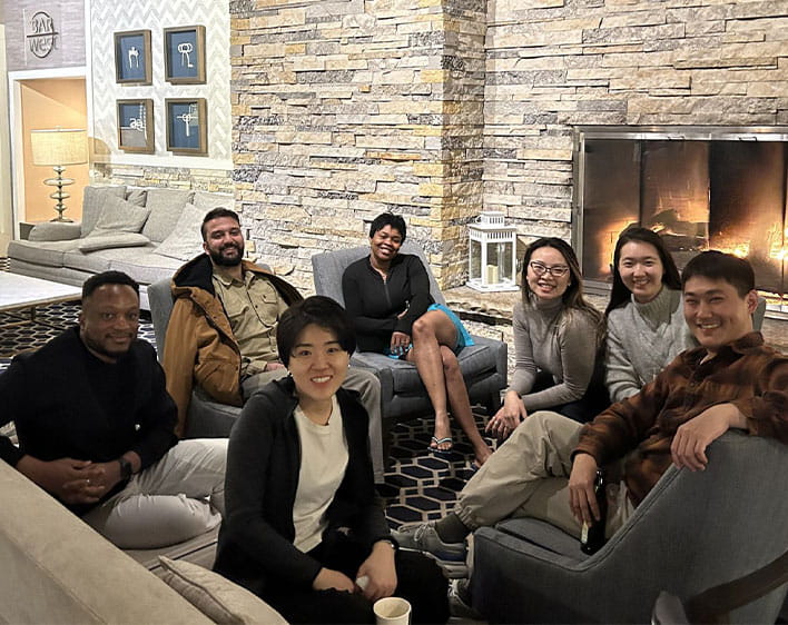 Ude Adekunle with Boothies sitting down smiling in front of fireplace