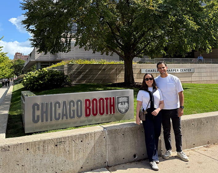 Ricardo Haneine Tame and partner in front of Chicago Booth sign at Harper Center