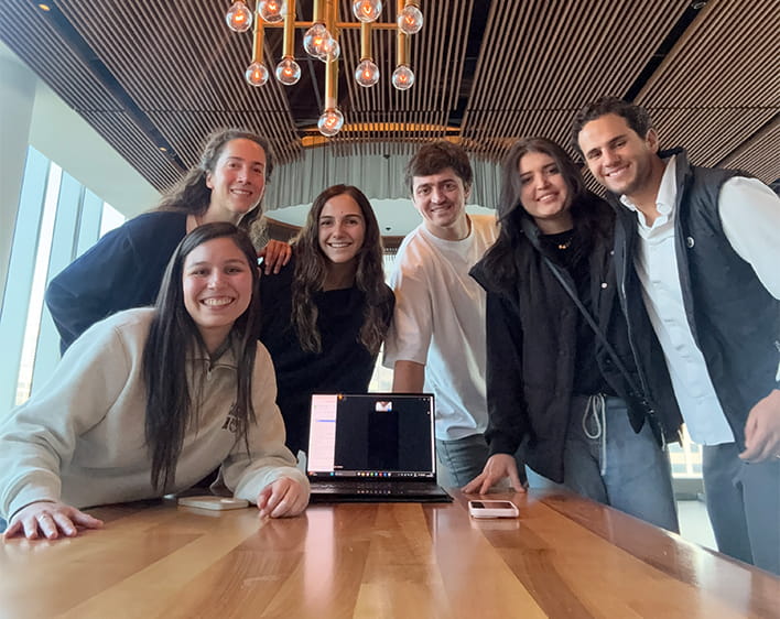 Ricardo Haneine Tame with Boothies smiling with laptop in center of table