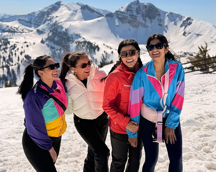Savita Gupta with friends from GWB on top of snowy mountain wearing winter gear smiling
