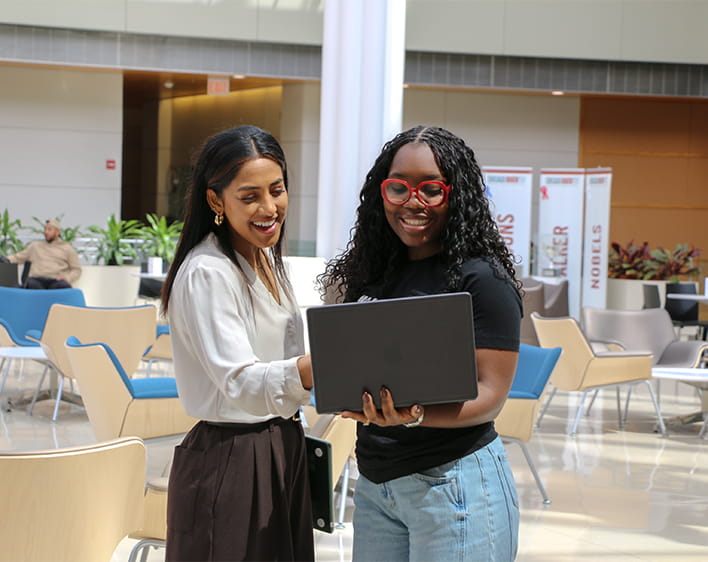 two women talking while looking on computer