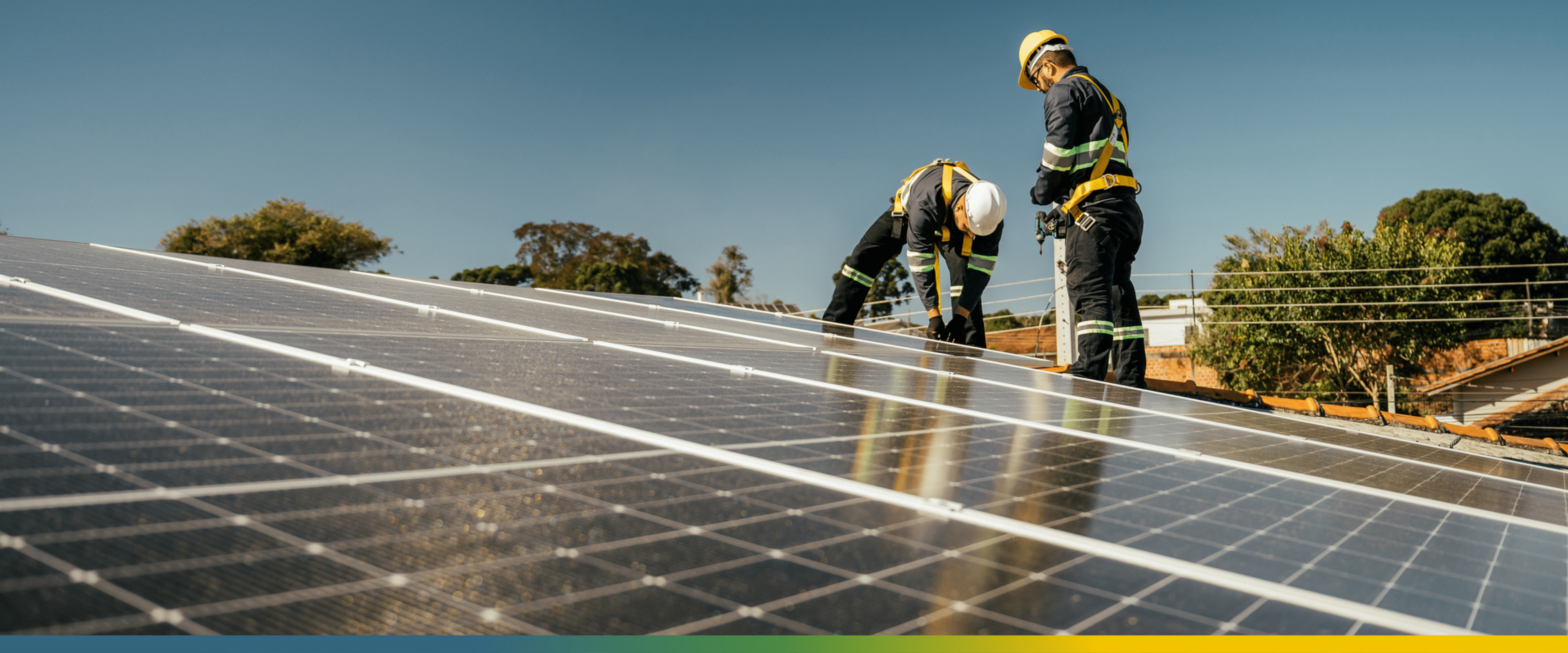 Two workers installing solar panels on roof