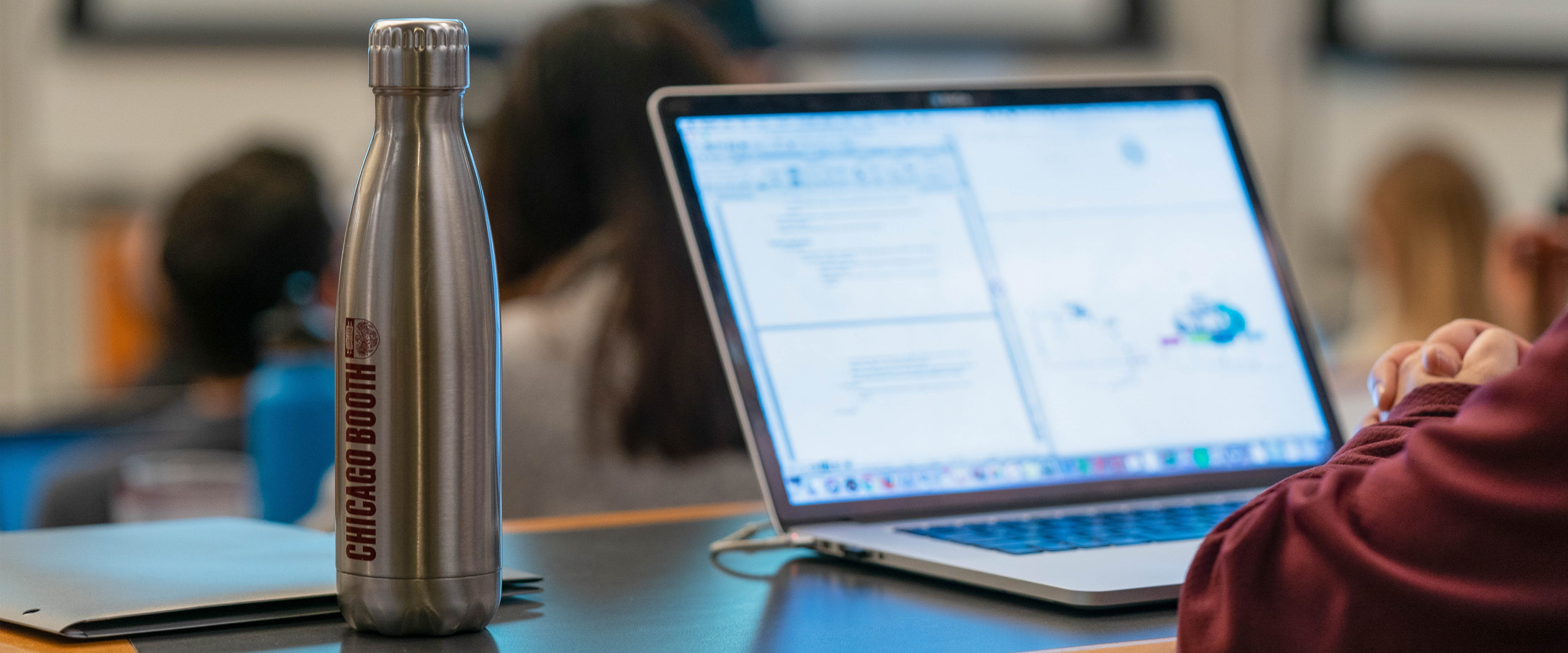 Student on a laptop with Chicago Booth water bottle
