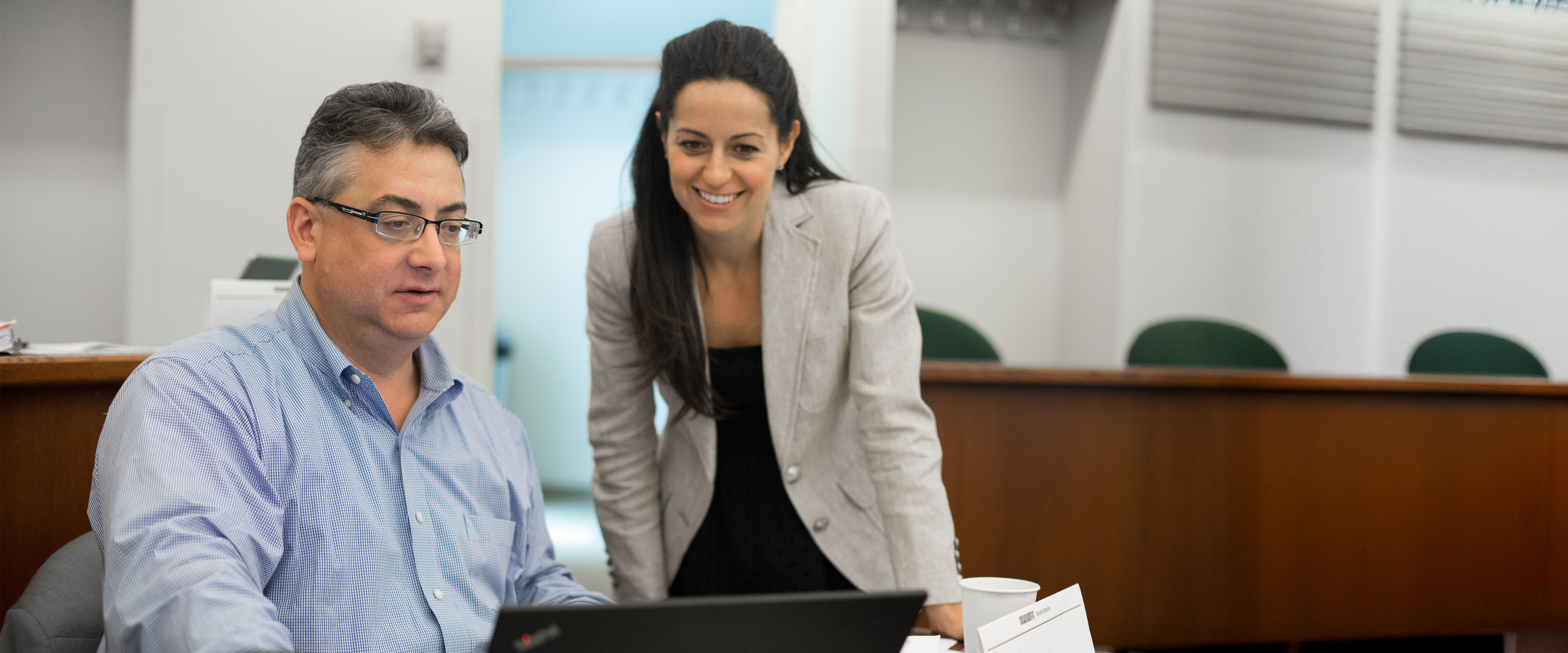 Two students looking at a laptop screen discussing